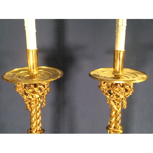 562 - A pair of Gothic influenced gilt brass floor standing Lamps with circular drip tray above three stem... 