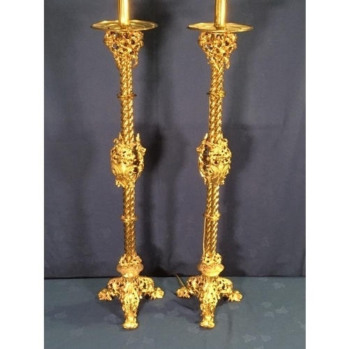 562 - A pair of Gothic influenced gilt brass floor standing Lamps with circular drip tray above three stem... 