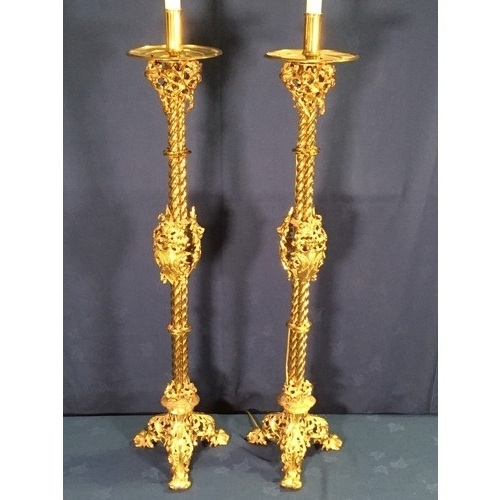 562 - A pair of Gothic influenced gilt brass floor standing Lamps with circular drip tray above three stem... 