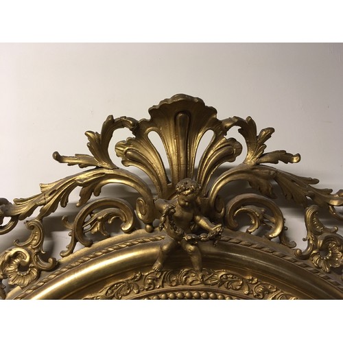 777 - A late 19th Century gilt framed large oval Wall Mirror with cherub and leafage surount and leafage m... 