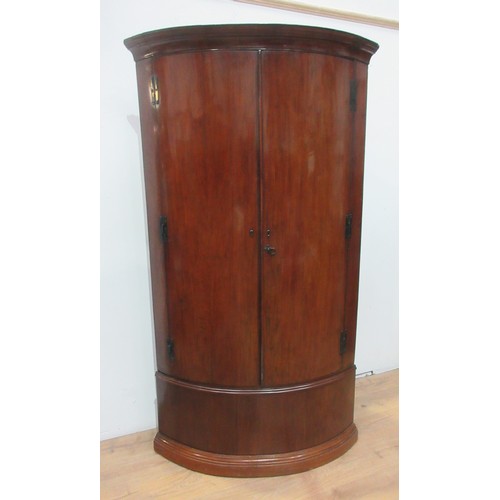 784 - A tall 19th Century mahogany Corner Cupboard with a pair of curved panelled doors, enclosing shelves... 