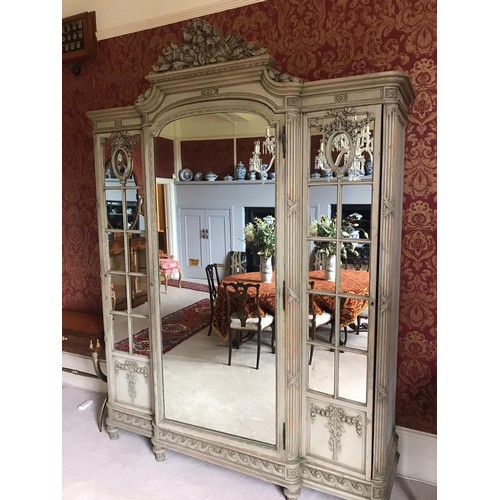 779 - A French green painted Cabinet fitted three mirror doors beneath floral and torch surmount all upon ... 