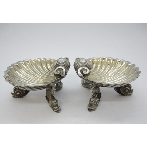 188 - A pair of Victorian silver scallop shape Salts on dolphin supports, London 1875.