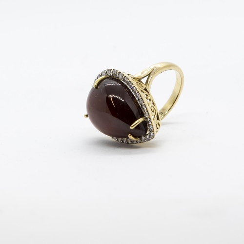 300 - A Garnet and Diamond Cocktail Ring, claw-set large pear-shaped garnet cabochon within frame of pavé-... 