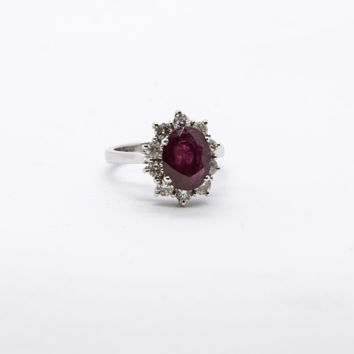 399 - A Ruby and Diamond Cluster Ring, claw-set, oval-cut ruby, 3.03cts, within a frame of ten brilliant-c... 