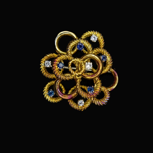 408 - A Diamond and Sapphire Brooch formed from numerous circles, claw-set five round sapphires and four b... 