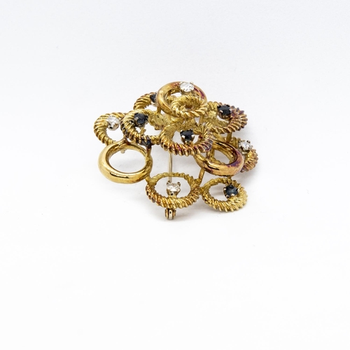 408 - A Diamond and Sapphire Brooch formed from numerous circles, claw-set five round sapphires and four b... 