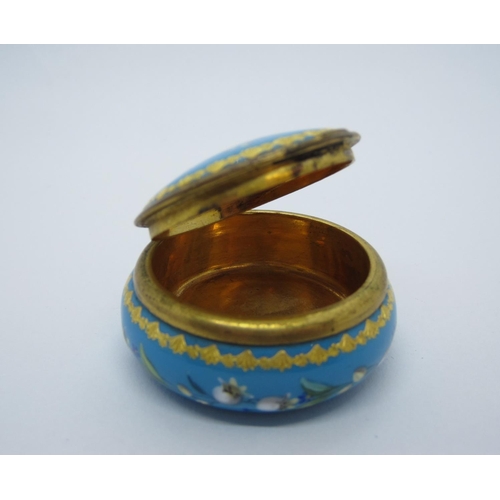 423 - A Turquoise Enamel Pill Box with hinged lid, decorated lily of the valley and gilt detail, 1 3/4 in ... 