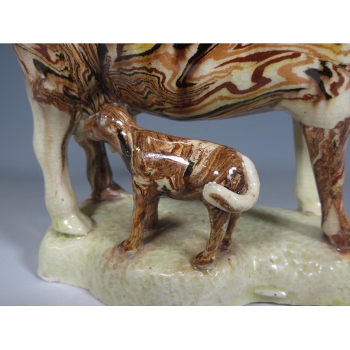 506 - An Agate ware Cow Creamer with calf at foot on a shaped platform base, the lid with moulded floral k... 