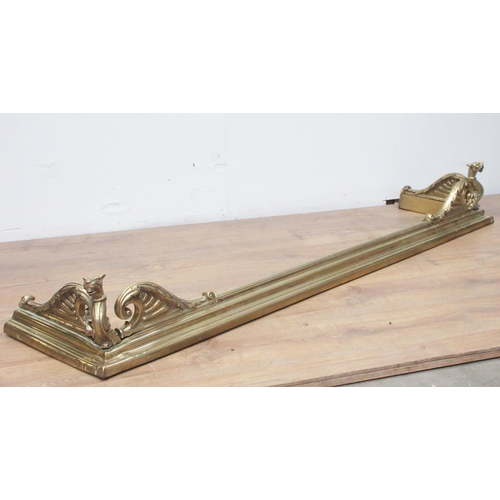 523 - A large brass fender with scrolled design and dragon's heads, 5ft 5in W