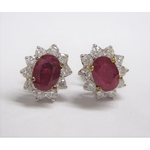 178 - A pair of Ruby and Diamond Cluster Earrings each claw set oval-cut ruby within frame of ten brillian... 