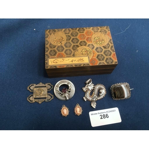 286 - A small lacquered Box, silver stag's head Brooch, dragon Brooch, agate Brooch, etc.