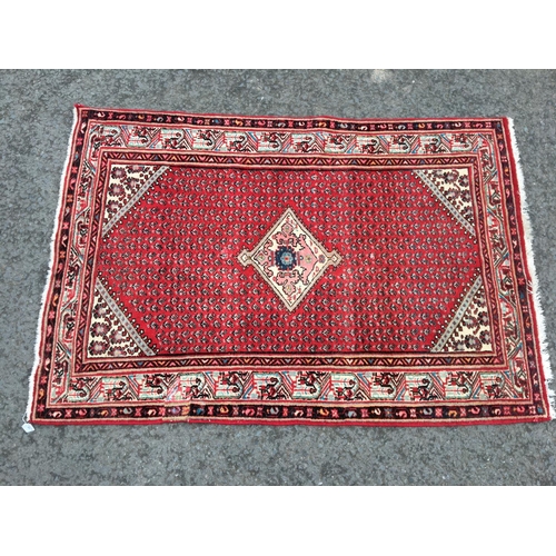 311 - A Persian style Rug, with central lozenge on a red ground 6ft 7in x 4ft 5in, repaired