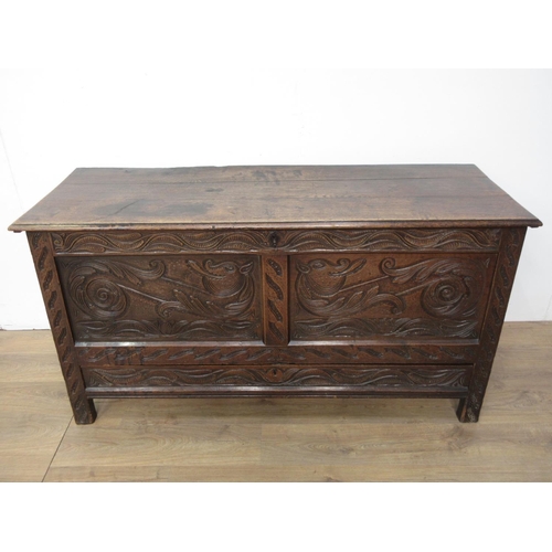 411 - An oak Coffer in the 17th Century style with moulded plank lid above dragon carved two panel front f... 