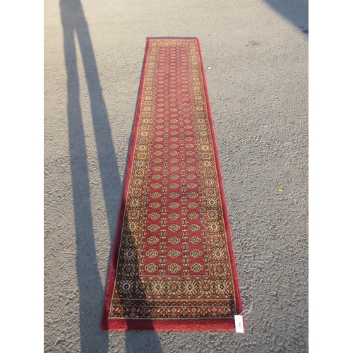 579 - A modern red ground Runner 10ft 11in L x 2ft 2in W