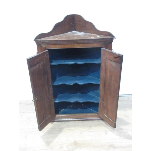 130 - An antique oak Hanging Corner Cupboard with raised back and pair of doors enclosing shaped shelves, ... 