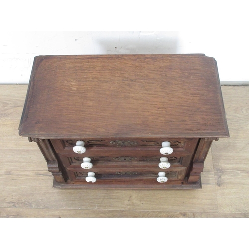 144 - An oak miniature Chest of drawers, with carved drawer fronts and ceramic knobs, 111/2in H x 14 1/2in... 