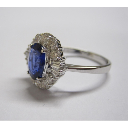 165 - A Sapphire and Diamond Cluster Ring claw-set oval-cut sapphire, 1.79cts, within frame of baguette an... 