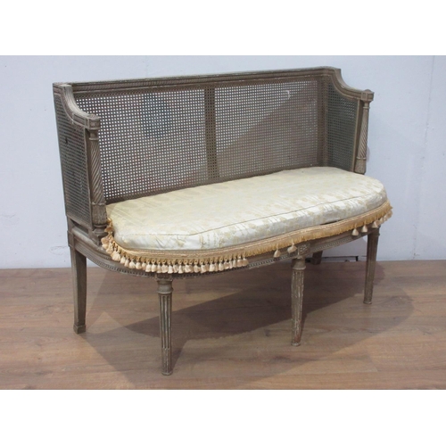 391 - A bergere and painted small Settee with cane panelled back and sides, upholstered seat on stop flute... 