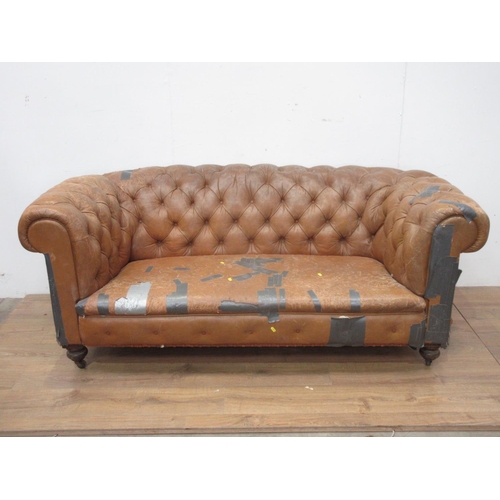 506 - A button upholstered leather Chesterfield on turned supports and casters 6ft 5 in W, in need of exte... 