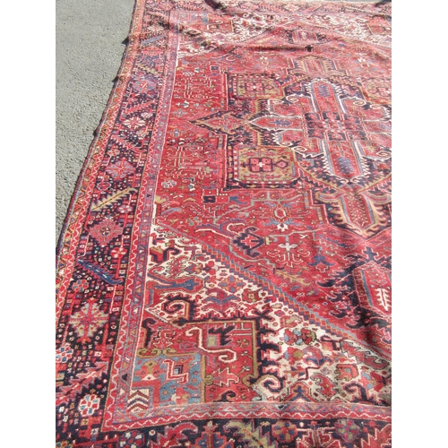 65 - A large woollen red ground Carpet with stylised floral central motif 13ft 2in L x 9ft 8in W