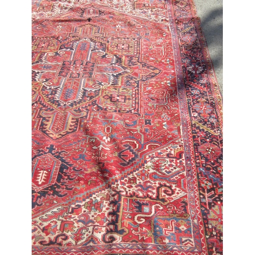 65 - A large woollen red ground Carpet with stylised floral central motif 13ft 2in L x 9ft 8in W