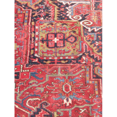 65 - A large woollen red ground Carpet with stylised floral central motif 13ft 2in L x 9ft 8in W