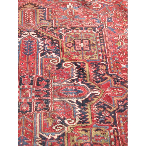 65 - A large woollen red ground Carpet with stylised floral central motif 13ft 2in L x 9ft 8in W