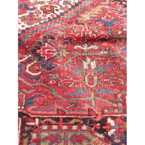 65 - A large woollen red ground Carpet with stylised floral central motif 13ft 2in L x 9ft 8in W