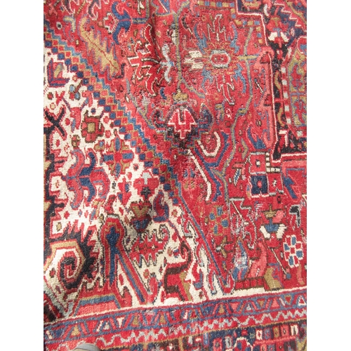 65 - A large woollen red ground Carpet with stylised floral central motif 13ft 2in L x 9ft 8in W