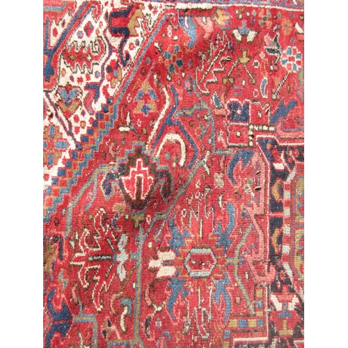 65 - A large woollen red ground Carpet with stylised floral central motif 13ft 2in L x 9ft 8in W