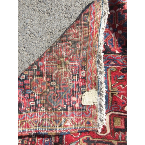 65 - A large woollen red ground Carpet with stylised floral central motif 13ft 2in L x 9ft 8in W