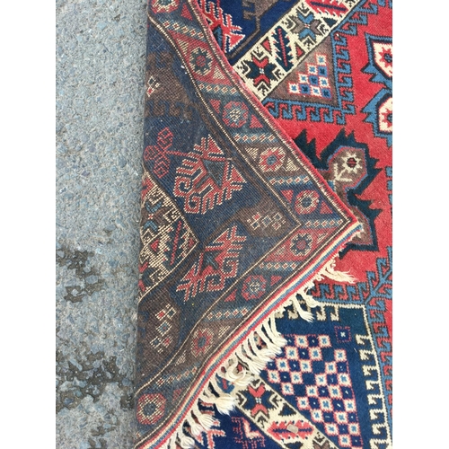 68 - A Persian Rug, multi-bordered with cross motifs on a red ground, 9 ft 8 in x 6 ft 8 in, some fading ... 