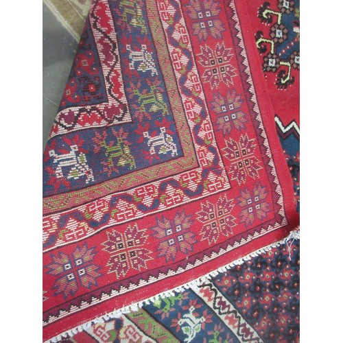 64 - A large woollen oriental Carpet with red ground and five blue lozenges 11ft 6in L x 8ft 10in W