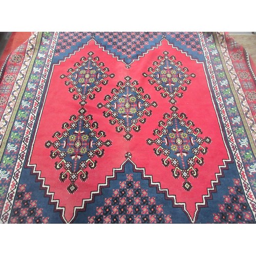 64 - A large woollen oriental Carpet with red ground and five blue lozenges 11ft 6in L x 8ft 10in W