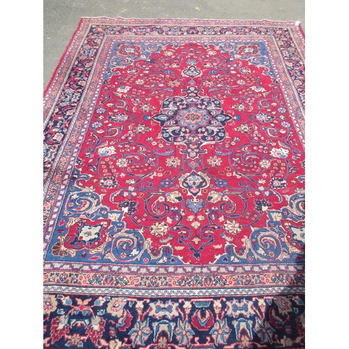 69 - A large woollen red ground Carpet with floral decoration within blue border 11ft 2in L x 6ft 1in W