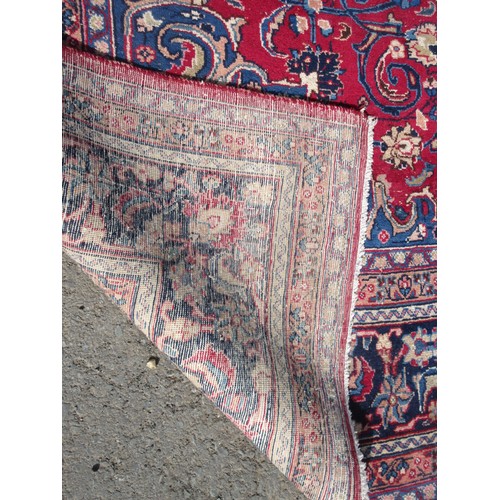 69 - A large woollen red ground Carpet with floral decoration within blue border 11ft 2in L x 6ft 1in W