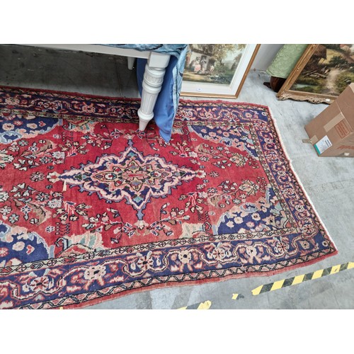 558 - A bordered Persian Rug on a red ground 8ft 2in x 4ft 5in A/F.