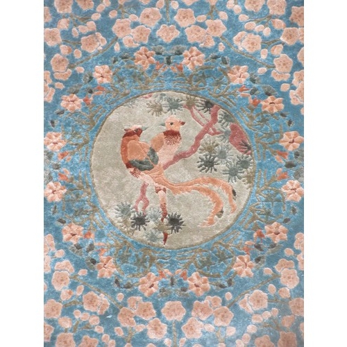 563 - A small bordered Rug with central panel of birds on a branch on a blue ground 6ft 2in x 4ft.