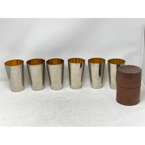 396 - A set of six plated graduated Beakers in fitted leather case bearing initials R.G.P. 5 1/2in