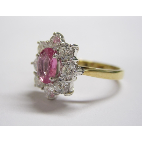 176 - A Pink Sapphire and Diamond Cluster Ring claw-set oval-cut sapphire, 0.90cts, within a frame of eigh... 