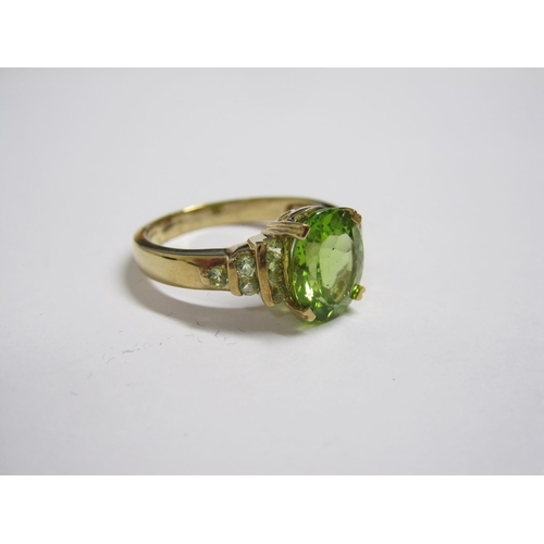 181 - A Peridot Ring claw-set oval-cut stone, smaller stones to shoulders in 9ct gold, ring size N.