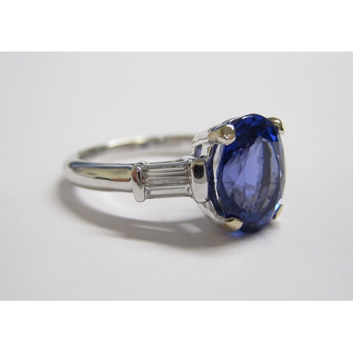 195 - A Tanzanite and Diamond Ring claw-set oval-cut tanzanite, 2.50cts, between two diamond baguettes in ... 