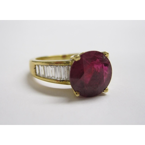 201 - A Ruby and Diamond Ring claw-set round ruby, 3.26cts, between channel-set graduated baguette diamond... 