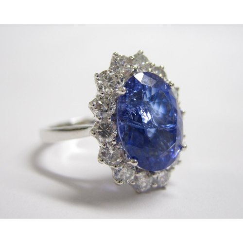 208 - A Tanzanite and Diamond Cluster Ring claw-set oval-cut tanzanite, 5.65cts, within a frame of fourtee... 