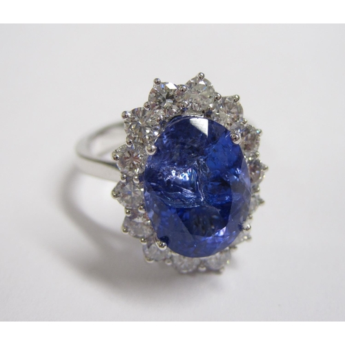 208 - A Tanzanite and Diamond Cluster Ring claw-set oval-cut tanzanite, 5.65cts, within a frame of fourtee... 