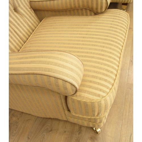 73 - A pair of Kirkdale button upholstered Armchairs with striped gold upholstery on brass front casters,... 