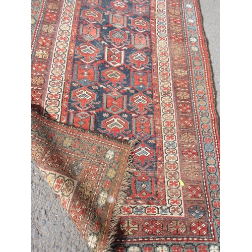 666 - A red ground woollen Rug with blue centre and tramline borders 8ft 3in x 3ft 6in and a red ground Pr... 