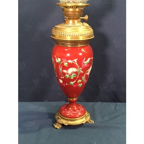 149 - An Oil Lamp with glass shade and brass reservoir mounted within a deep red ground porcelain baluster... 