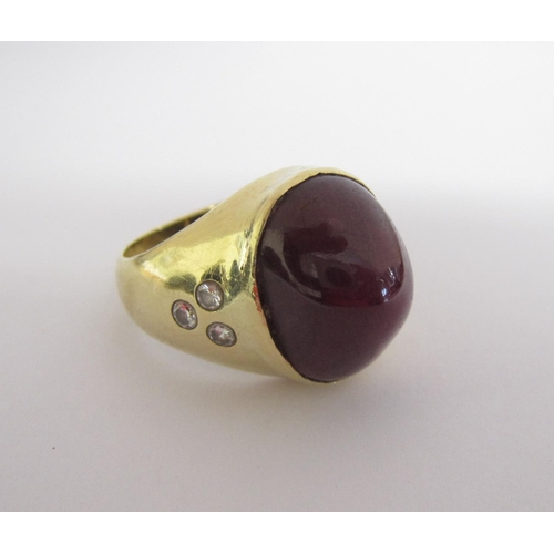 164 - A Ruby and Diamond Ring set large oval ruby cabochon, 22cts, between trios of gypsy-set brilliant-cu... 